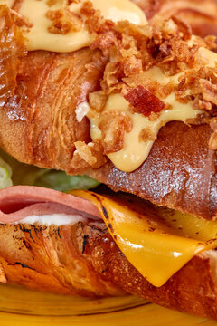 Delicious croissant sandwich dripping with melted cheddar cheese and crispy fried onions