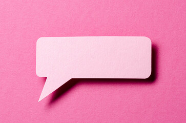 Paper speech bubble with shadow and copy space for text on pink background, close-up flat lay top...