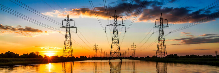 high voltage electric towers,dramatic sunset sky,power lines over lake,landscape with electricity pylons,industrial panorama at dusk
