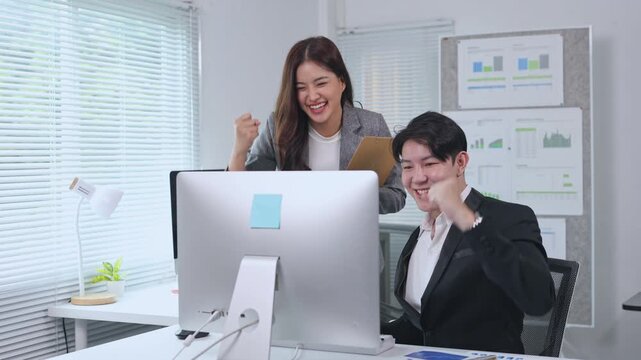 Professional team celebrating project success, viewing collaborative results on computer screen and exchanging high fives in bright modern office workspace