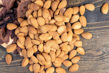 Obraz premium dried almonds scattered on a wooden table, edible delicious and crunchy brown almonds, closeup