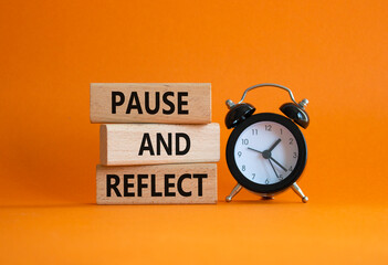 Pause and Reflect symbol. Concept words Pause and Reflect on wooden blocks. Beautiful orange...