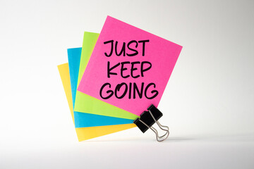 Just keep going symbol. Pink sticky note with paper clips with words Just keep going. Beautiful...