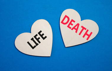 Life or Death symbol. Concept word Life or Death on wooden hearts. Beautiful blue background....