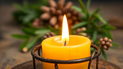 A warm, glowing candle surrounded by pinecones and green branches. Perfect for winter, holiday, or cozy atmosphere themes.