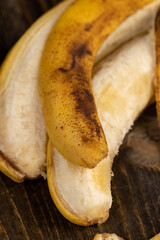 banana on a black pine wood table , blackening old ripe banana whose color changes from yellow to...