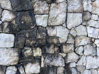 Old rough stone wall texture background with various stone sizes, ideal for rustic design or rustic wall background.