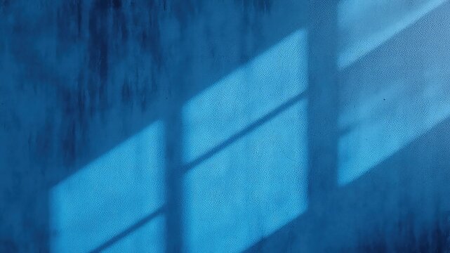 Indigo blue textured wall displaying an abstract shadow pattern from a window casting light. - Powered by Adobe
