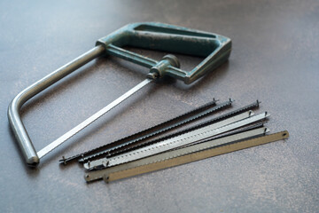 A hand-held metal hacksaw with saws is on the table. A tool for cutting metal.