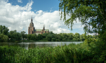 A picturesque view of the historic Greifswald Cathedral, a brick gothic church seen across a tranquil river. Picture taken on a holiday trip to Greifswald, Germany with my Sony a7III