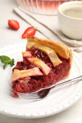 Piece of tasty strawberry pie and berries on white wooden table, closeup