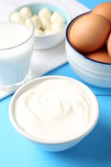Different dairy products and eggs on light blue wooden table, closeup