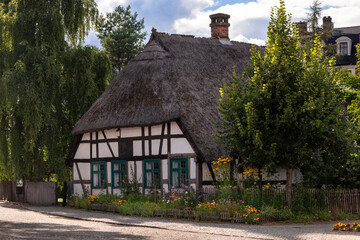 Stare zabudowania, domy szachulcowe z elementami roślinnymi, kwiatami i drzewkami.  © Magdalena