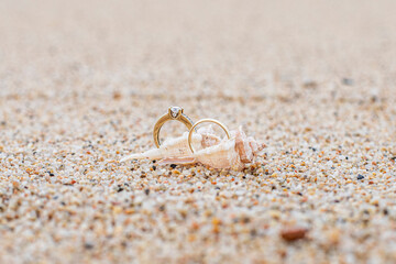 Close-up of wedding rings on the sand. Engagement, background with space for text. Wedding details in a marine theme