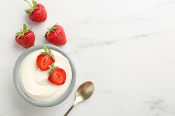 Delicious yogurt in bowl, strawberries and spoon on white marble table, flat lay. Space for text