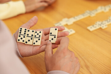 Friends playing dominoes at wooden table, closeup