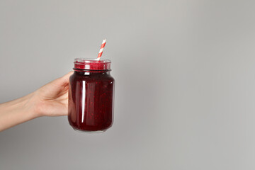 Superfood. Woman with mason jar of tasty smoothie against grey background, closeup. Space for text