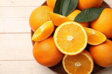 Fresh ripe oranges and leaves on light wooden table, top view. Space for text
