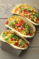 Tasty vegetarian tacos with chickpeas, corn and quinoa served on wooden table, top view