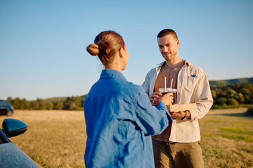 Young couple sharing refreshing drinks and enjoying a delicious takeaway meal in the great outdoors...