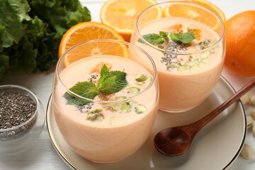Superfood. Tasty smoothie with chia seeds, mint, pistachio and oranges on white wooden table, closeup