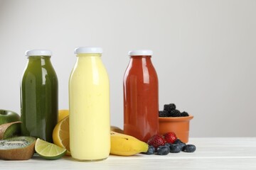 Superfood. Bottles with tasty smoothies and ingredients on white wooden table against light grey...