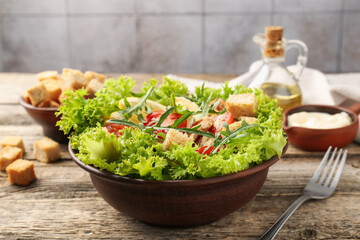 Delicious salad with croutons served on wooden table, closeup