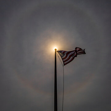 The American stars and stripes flag waving in the middle of sunbow halo