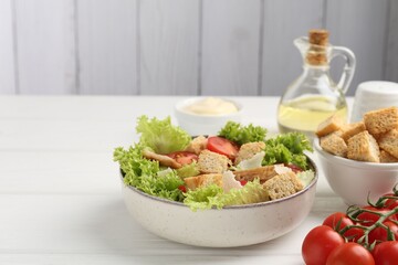 Delicious salad with croutons and ingredients on white wooden table, closeup. Space for text
