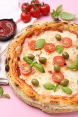Delicious pizza and ingredients on pink table, closeup