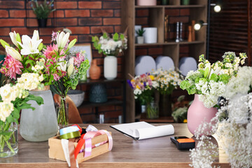 Beautiful flowers, ribbons and other tools on wooden table in florist's shop