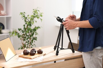 Man taking picture of chocolate muffins in studio, closeup. Professional food photography