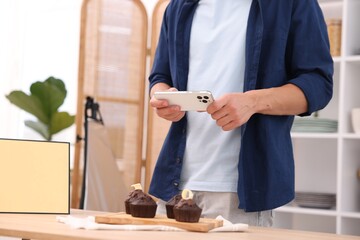 Man taking picture of chocolate muffins in studio, closeup. Professional food photography