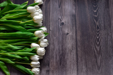 Manu white tulips on wooden background. Lying spring bouquet of white tulips on wooden table....