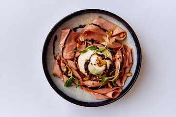 A Creative Culinary Presentation Featuring Delicately Arranged Cold Cuts and Creamy Burrata on a Tastefully Decorated Plate with a Drizzle of Balsamic Reduction.