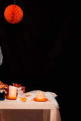 Halloween party decorations illuminating dark background with candles and paper ball