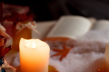 Burning candle illuminating halloween decorations and open book