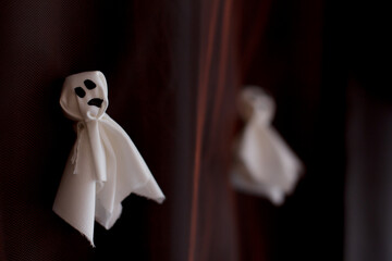 Friendly ghost decorations hanging on dark curtain for halloween party