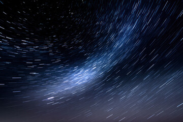 Star trails create dynamic patterns in the night sky, capturing celestial movement above a calm and quiet landscape