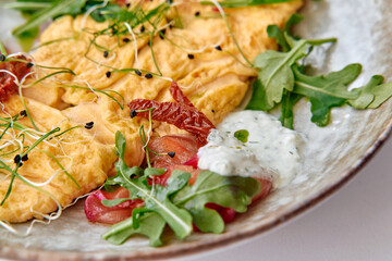 Delicious Gourmet Omelette Served with Fresh Greens, Sprouts, and Zesty Sauce on a Stylish Plate, Perfect for a Nutritious Breakfast Experience