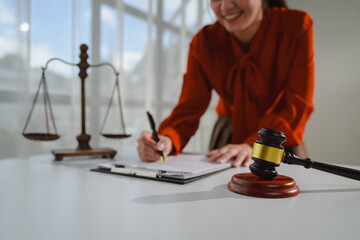 Lawyer signing legal document with gavel and scales of justice on table