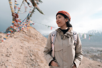 Woman traveler explores Leh Ladakh, India, walking beside colorful Tibetan prayer flags, embracing Himalayan culture, spiritual atmosphere on adventurous mountain journey
