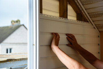 Installation of siding on the walls around the balcony window.