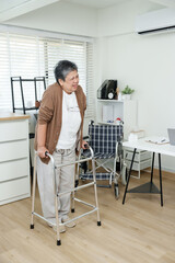 Senior asian woman smiles slightly while walking with walker inside rehabilitation room during...
