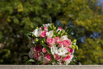 Wedding bouquet resting on stone surface with blurred foliage background