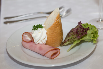 Wedding appetizer with ham, bread, cream and lettuce on white plate