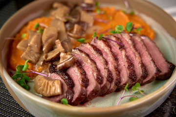 A Gourmet Dish Featuring Succulent Sliced Duck Breast and Savory Mushroom Medley on a Bed of Creamy Sweet Potato Purée, Perfect for Culinary Enthusiasts