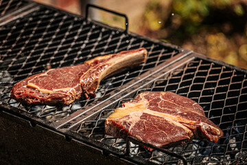 A thick-cut raw tomahawk steak rests on a hot metal grill, showcasing rich marbling and a long bone handle. Ideal for barbecue or steakhouse-style cooking.