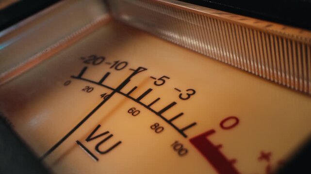 Analog dial indicator of audio signal level amplifier. Vintage arrow moves with sound level. Round classic volume indicator with yellow backlight, VU meters. Close-up of old measuring dB decibels