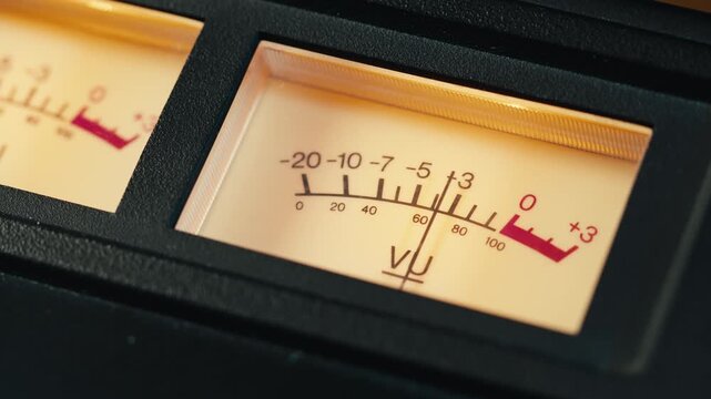 Analog dial indicator of audio signal level amplifier. Vintage arrow moves with sound level. Round classic volume indicator with yellow backlight, VU meters. Close-up of old measuring dB decibels